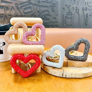 Sparkly hollow heart-shaped rhinestone keychains in five colors on a wooden tray display