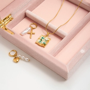 Detail of vintage gold butterfly window necklace and pearl earrings on pink velvet