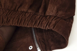 Details einer braunen Wildlederjacke mit elastischem Bund und Metall-Reißverschluss