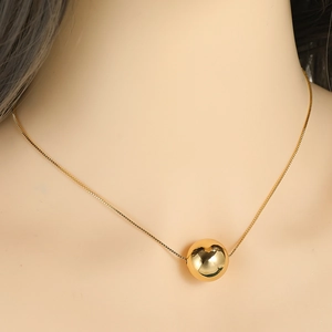 Detailaufnahme einer minimalistischen Goldkugelkette mit feiner Gliederkette an einem Modell