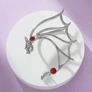 Macro detail of silver punk dragon ear cuff featuring intricate wings and red zircon eyes