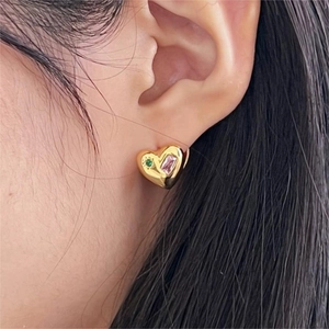 Detail of gold heart earrings with pink rectangular and green round crystals