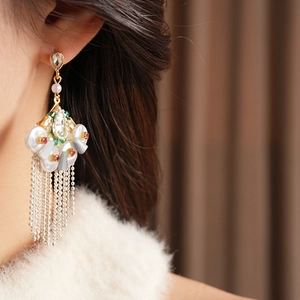 Detail of vintage fan-shaped earrings with pearls and long metal tassels on model