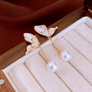 Detailed close-up of a butterfly drop earring with zircon and pearl in a jewelry box