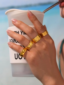 Detailed close-up of four-piece gold ring set featuring smiley face and beaded textures