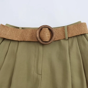 Close-up of olive green casual shorts featuring a woven belt with a round wooden buckle