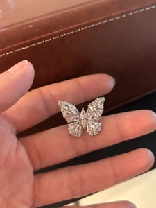 Detail of silver butterfly ear cuff with sparkling zircon inlay held by hand
