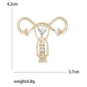 Golden uterus brooch with heart crystal, pearls and rhinestones on white background