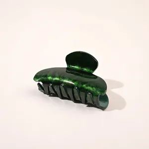 Close-up of a large dark green acetate hair claw clip with elegant marble texture
