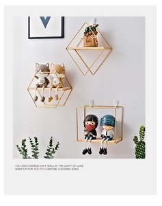 Detail view of geometric metal wall shelves with gold finish and natural wood base