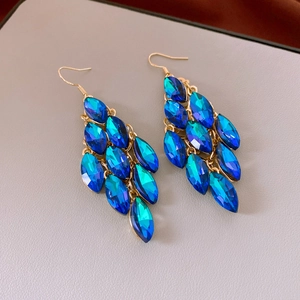 Close-up of deep blue crystal tassel earrings with multi-layered gold metal hooks
