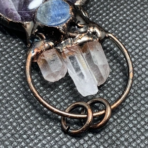 Macro detail of raw amethyst and white crystal column pendant in vintage bronze finish
