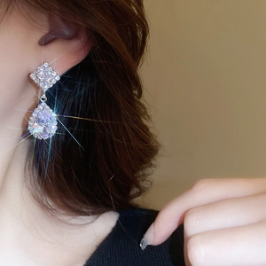Close-up of elegant silver drop earrings with sparkling square and teardrop zircon crystals