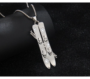 Detailed view of silver stainless steel ski and pole pendant with snowflake on box chain