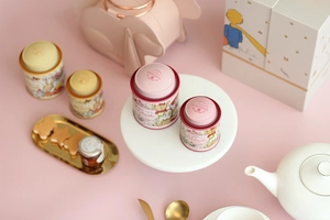 Close-up of pink and yellow tinplate tea canisters in a refined afternoon tea setting