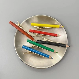 Détail de barrettes à cheveux colorées en forme de crayon sur un plateau en métal
