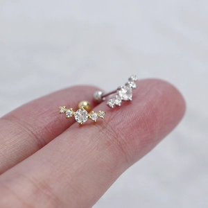 Macro shot of gold and silver curved zircon earrings held on a finger for size