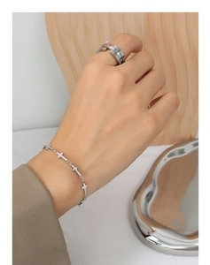 Macro detail showing the cross-link chain bracelet and bold ring in silver finish