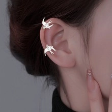 Detailed close-up of a silver swallow bird ear cuff worn on the earlobe without piercing