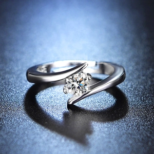 Detail of a sparkling one-carat moissanite ring with a twisted silver band on a blue background