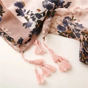 Detail of red floral print scarf with soft pink tassels and lightweight linen feel texture