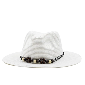 Détail d'un chapeau Fedora en paille blanche avec texture tissée et perles en bois
