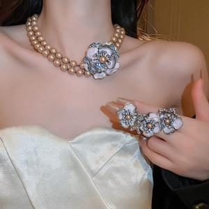Detailed view of champagne pearl necklace with enamel flower pendant and matching cocktail ring