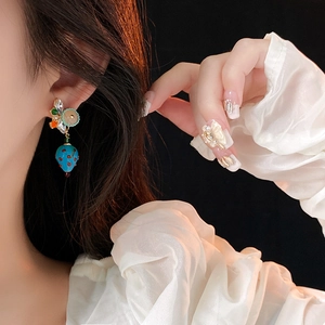 Close-up of vintage strawberry earrings in blue and red crystal on female model