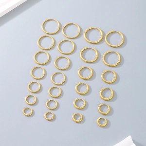 Flat lay of multiple gold polished hoop earrings in various sizes on grey surface