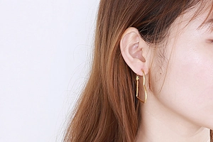 Close-up of a model wearing stylish gold heart-shaped titanium steel earrings