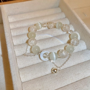 Detail shot of a beaded cat-eye stone moon bracelet with small bell on a jewelry tray