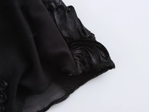 Close-up of black mesh fabric with glossy satin ruffled edges on an elegant blouse