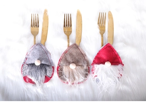 Three gnome Christmas cutlery holders in gray, brown and red on soft white plush