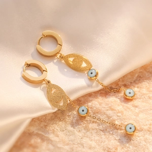 Creative gold evil eye drop earrings with long chain and round beads on silk background