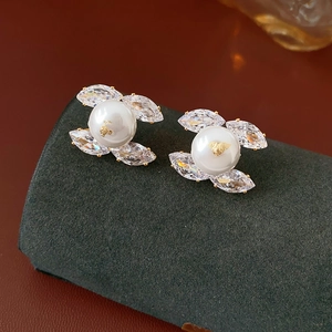 Macro detail of double C earrings with pearls and zircons on dark velvet surface