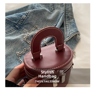 Détail du sac cylindrique en cuir bordeaux avec surpiqûres blanches et chaîne argentée