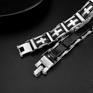 Close-up of stainless steel cross bracelet with black rubber and engraved clasp detail