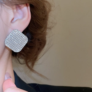 Primo piano di orecchini a lobo quadrati con strass lucidi indossati da una modella