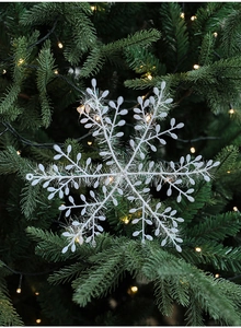 Close-up of white snowflake ornament on a Christmas tree with warm glowing lights