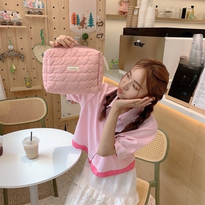 Detailed view of pink heart quilted cosmetic bag with branded label in lifestyle setting