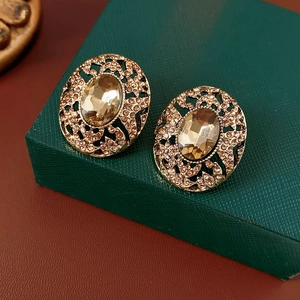 Close-up of vintage gold oval earrings with champagne gemstone and hollowed rhinestone details