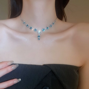 Close-up of elegant Y-shaped necklace with blue gemstones and diamonds on model neck
