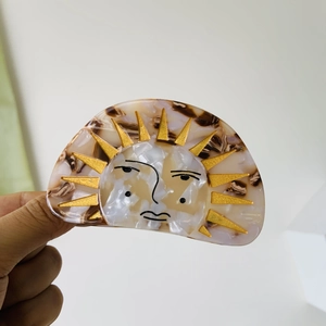 Detailed view of sun face hair claw clip made of golden and amber acetate resin