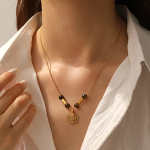 Detailed view of model wearing a vintage shell pendant necklace with tiger eye beads
