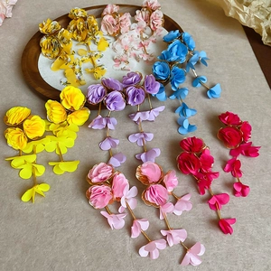 Macro shot of colorful chiffon flower tassel earrings displayed on a round wooden plate