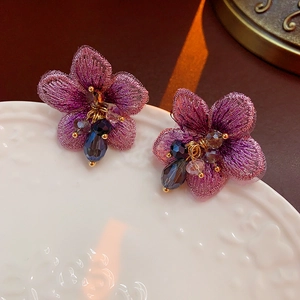 Dettaglio macro di orecchini a fiore ricamati viola con perline di cristallo e oro