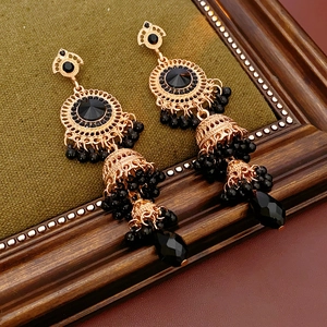 Detail of vintage gold earrings with black stones and water drop crystals on green fabric