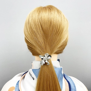 Close-up of a silver flower ponytail holder with rhinestones on golden hair