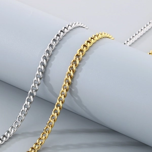 Detail of silver and gold Cuban link chains draped on a minimalist display