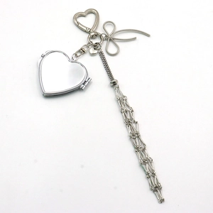 Detail of silver heart-shaped mirror pendant with bow and long chain tassels